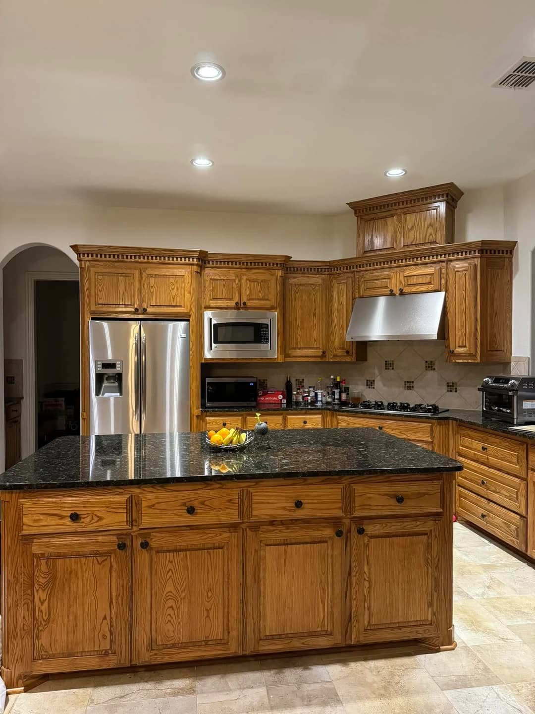A client's kitchen with dated honey-oak cabinets and black granite, photographed on a phone